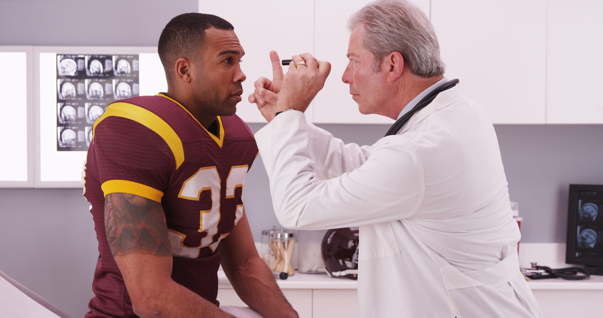 College football player having senior doctor review his concussion injury.